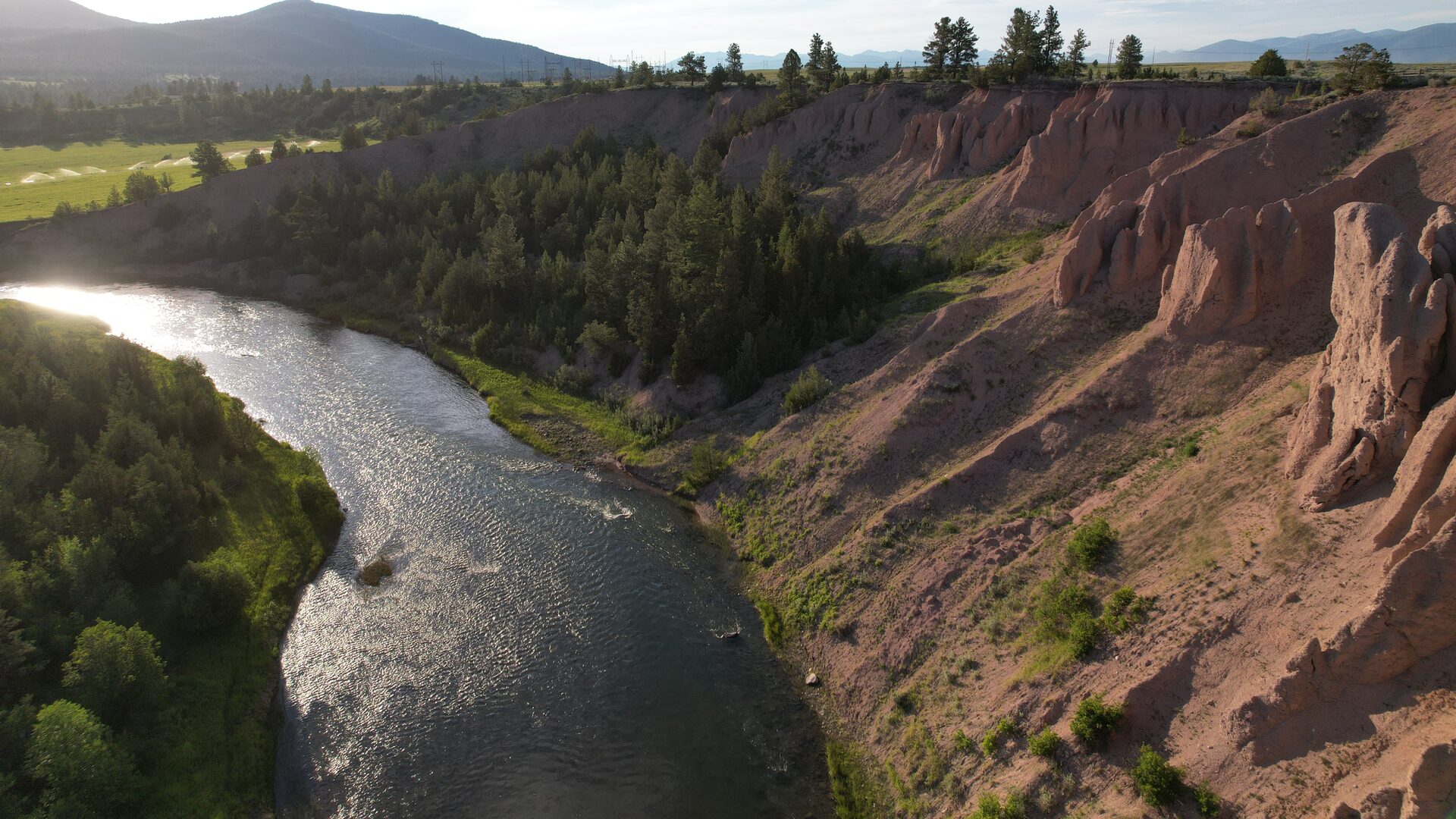 The Blackfoot River curving below red bluffs in evening light