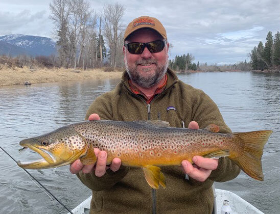 Brandon Boedecker holding a brown trout on the river
