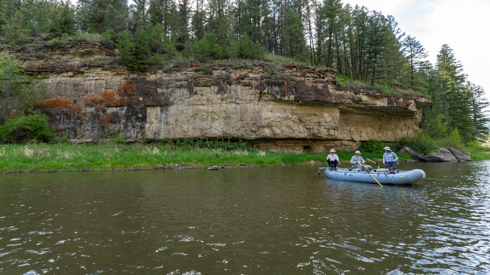 A guided raft drifting beneath a limestone ledge on the Smith River
